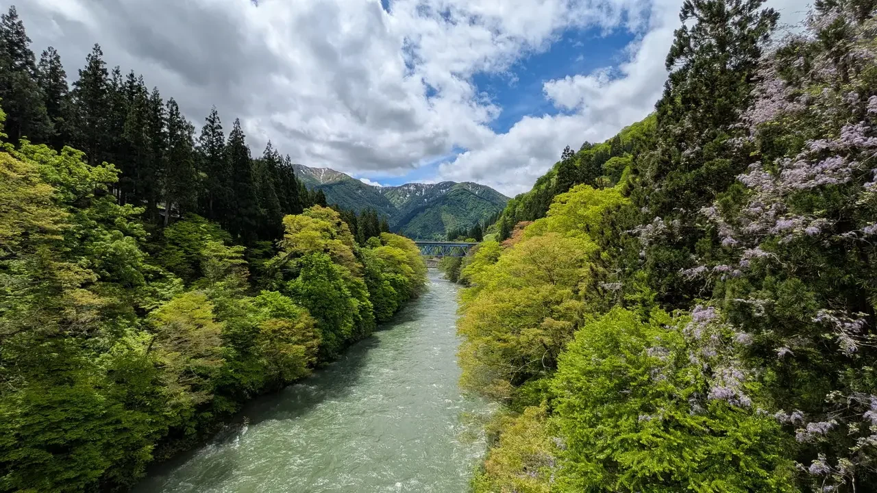 Un fiume verde scorre attraverso una valle boscosa e montuosa in Giappone.