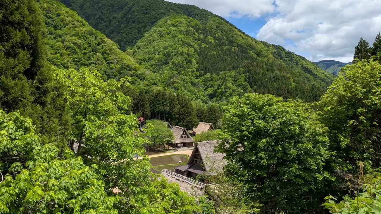 Case tradizionali con tetti di paglia immerse in una valle montuosa giapponese.