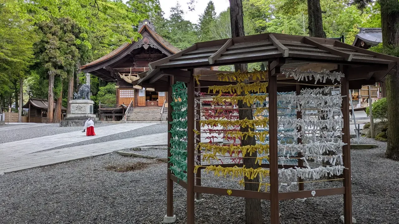 Un tempio tradizionale giapponese con decorazioni pendenti si trova in un parco alberato.