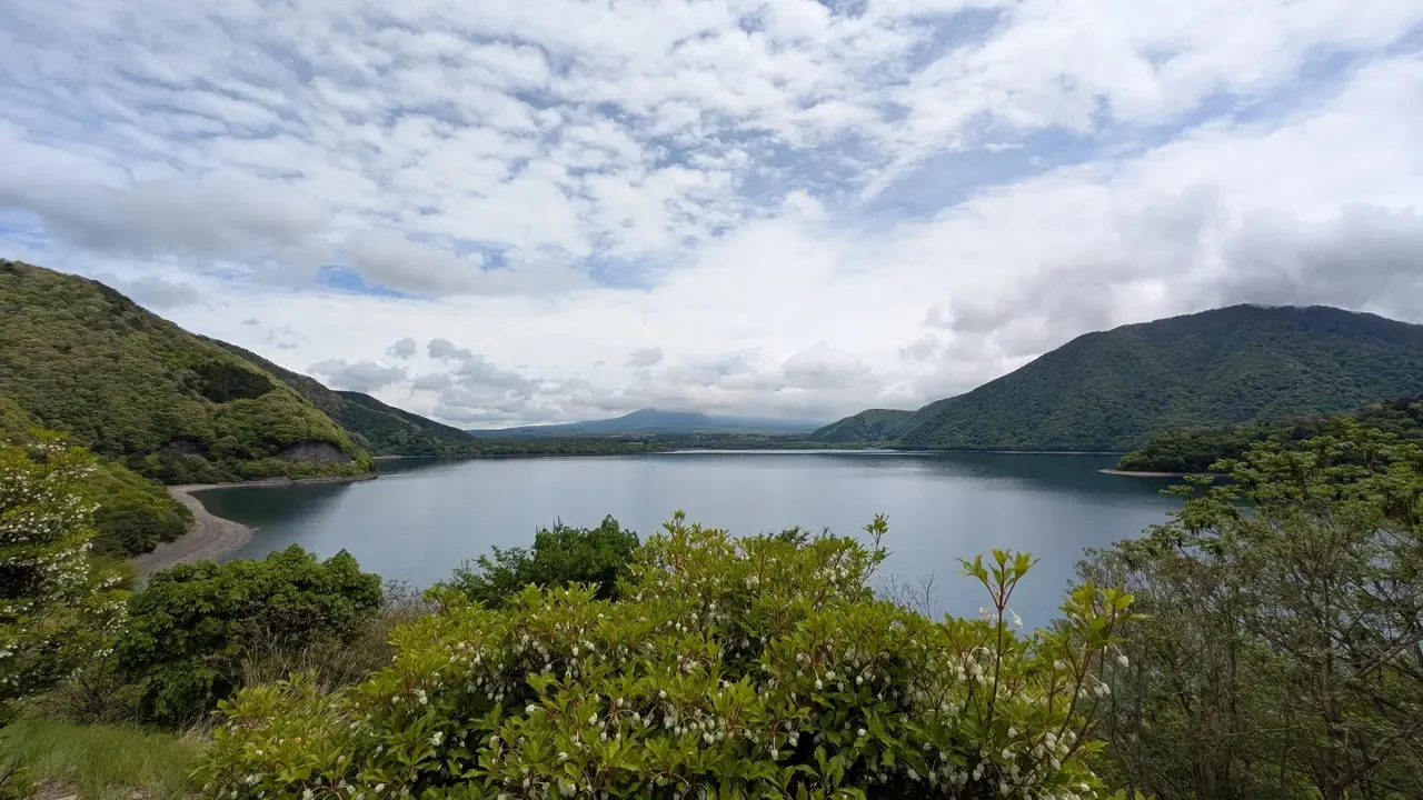 Un lago tranquillo circondato da colline verdi e nuvole.
