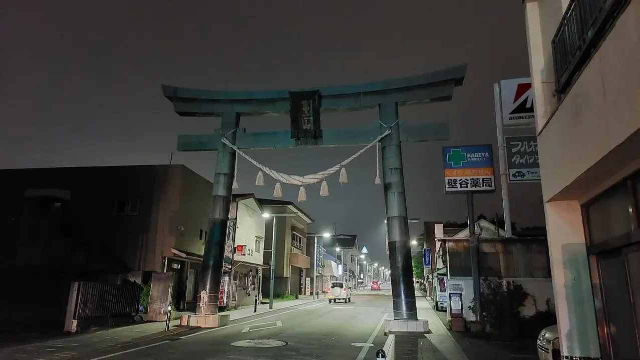 Un cancello torii in legno si estende lungo una strada giapponese al crepuscolo.