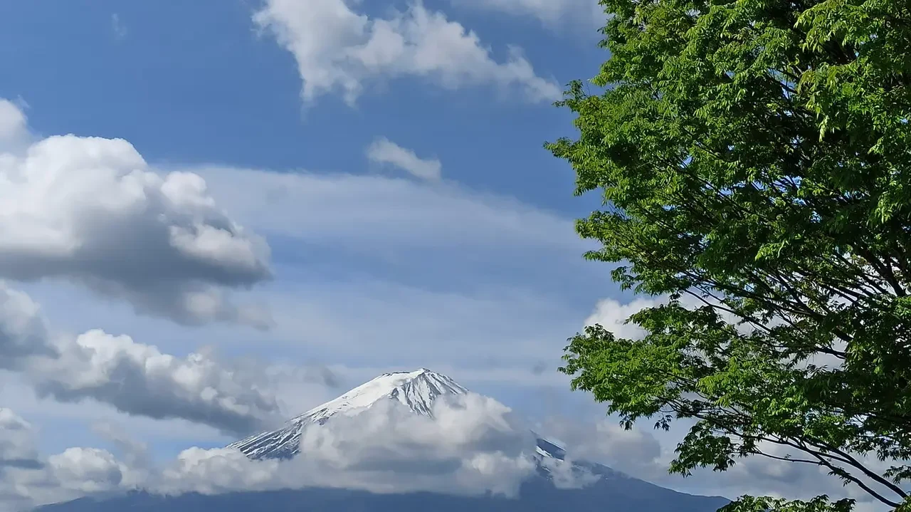 Il Monte Fuji è coperto da nuvole mentre si staglia contro il cielo azzurro.