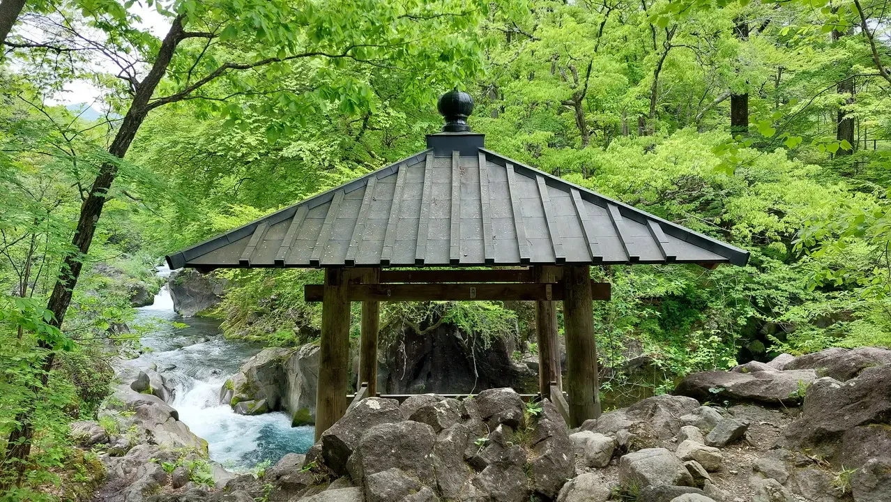 Una struttura in legno attraversa un fiume roccioso nel paesaggio naturale giapponese.