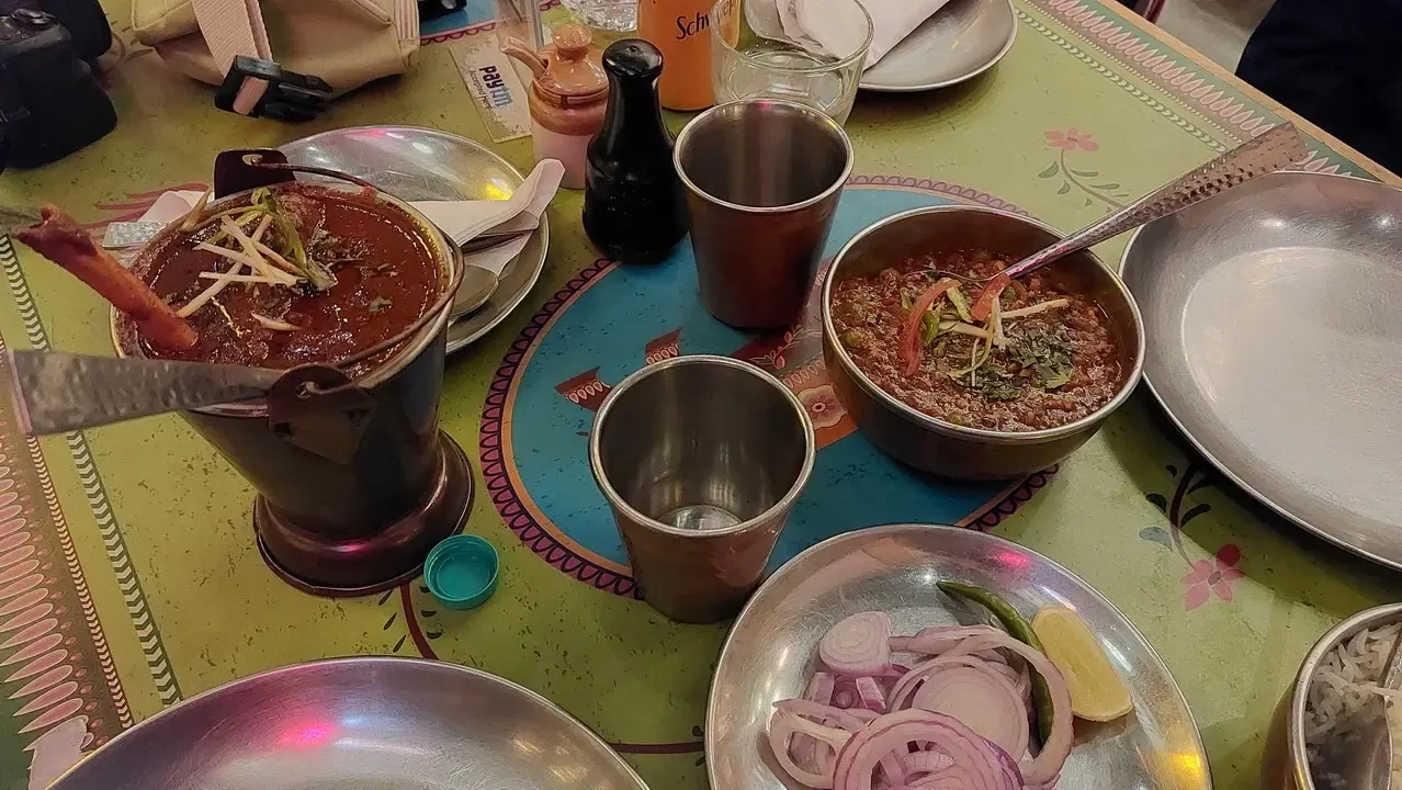 Un pasto indiano servito su una tovaglia colorata con diversi piatti di curry e verdure fresche.