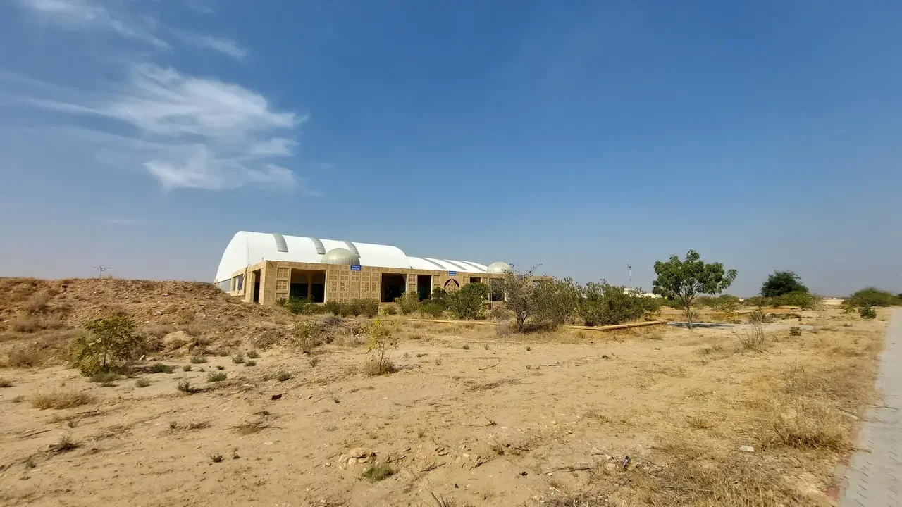 Un edificio in pietra si trova in un paesaggio arido sotto il cielo azzurro.