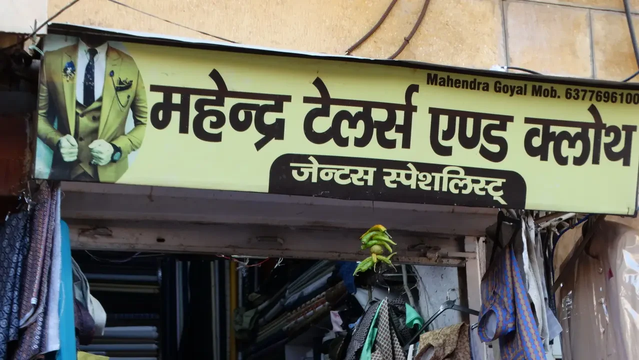 Una vetrina mostra abiti e tessuti appesi all'esterno di un negozio in India.