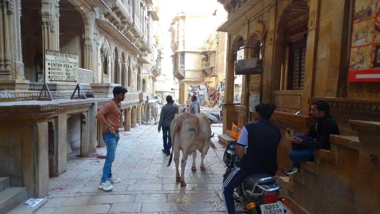 Una strada storica indiana con edifici in pietra e persone passeggiano.