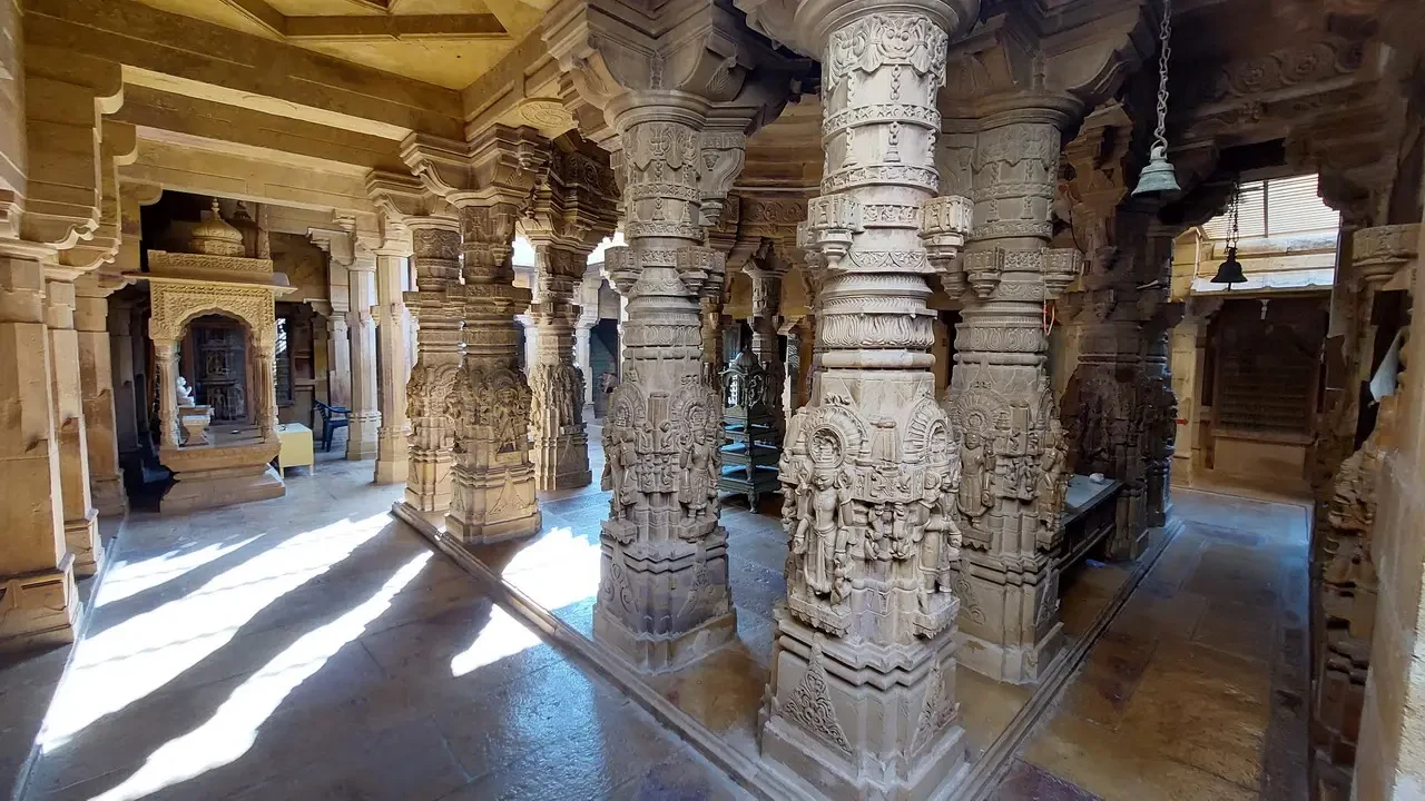 Interni di un antico tempio indiano con colonne scolpite e soffitto a volta.