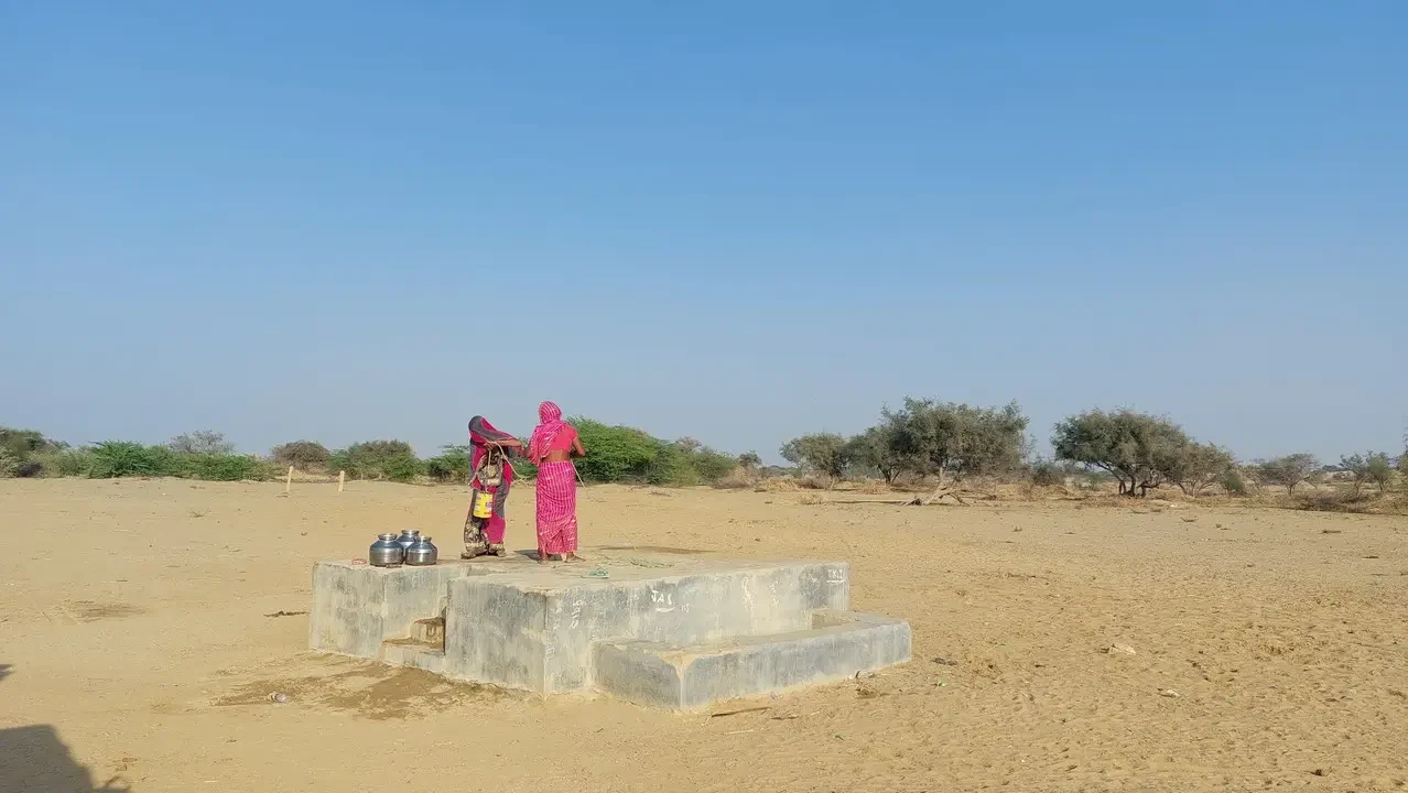 Due persone in sari stanno in piedi su una piattaforma di pietra nel deserto indiano.