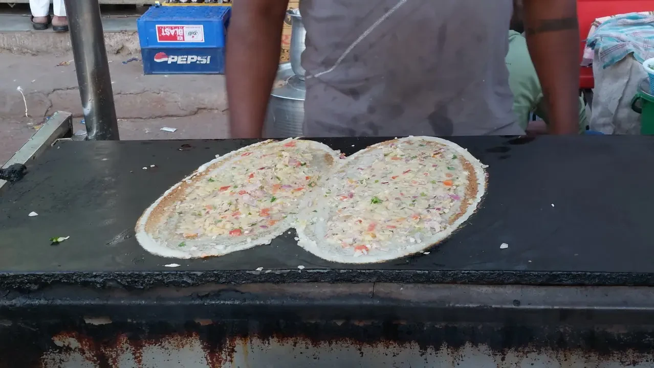 Cibi da strada vengono preparati su una piastra all'aperto in India.