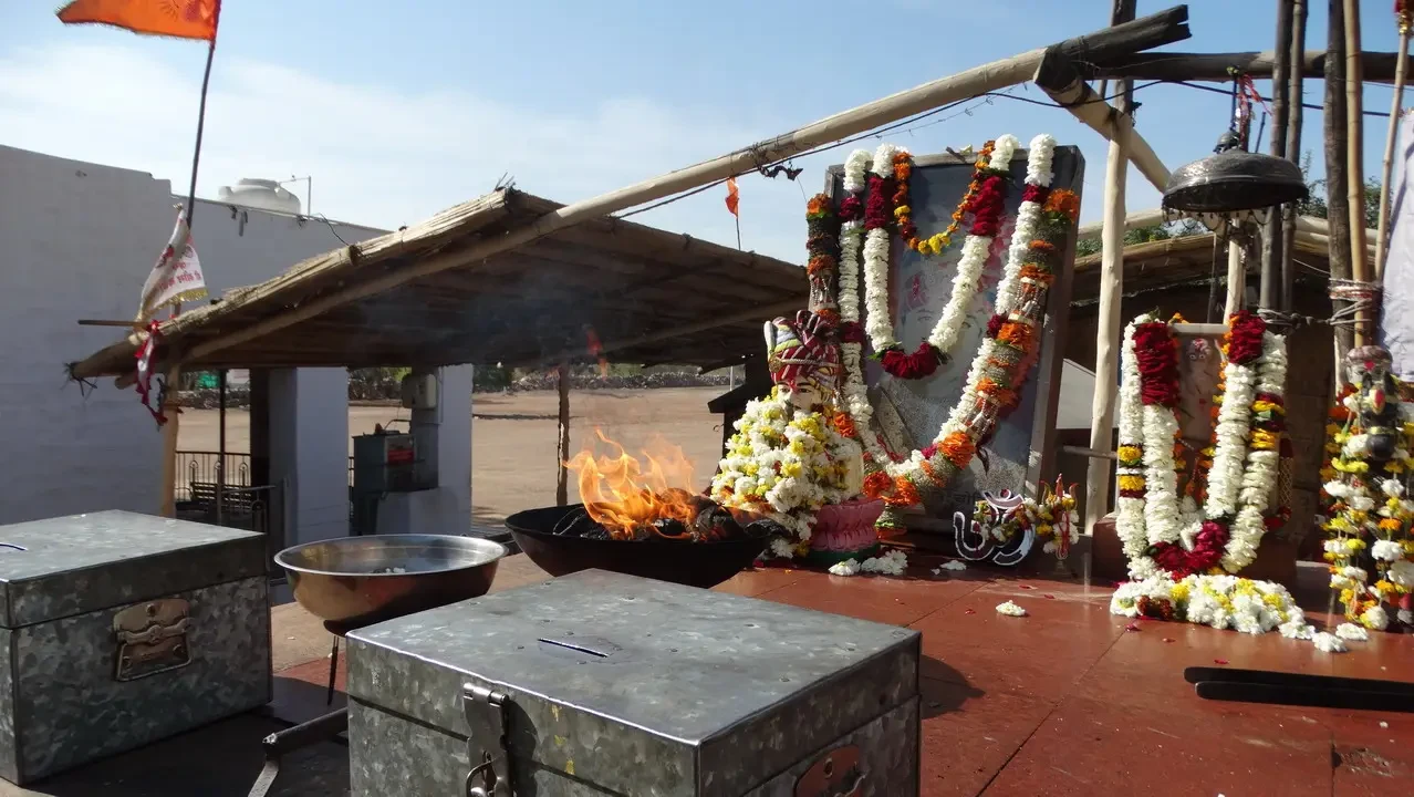 An altar with floral decorations is visible outdoors in India.