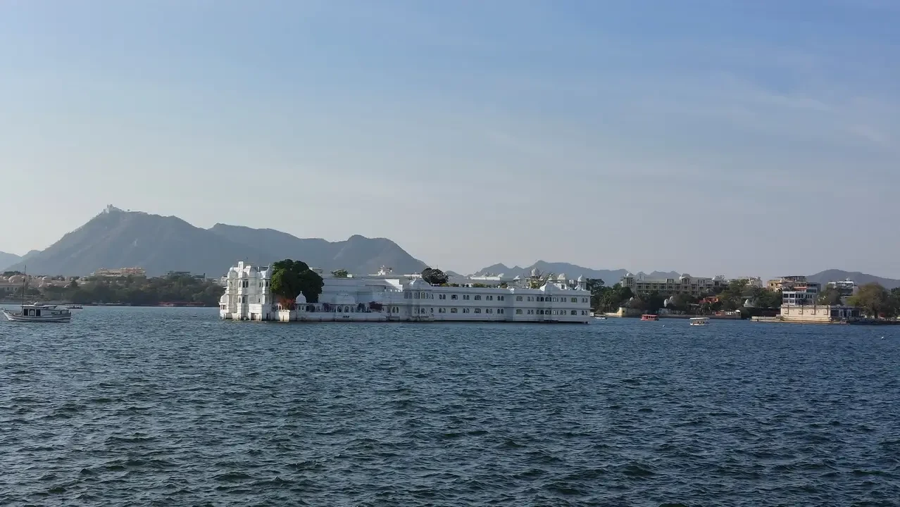 Una grande residenza bianca si staglia sull'acqua tra le colline.