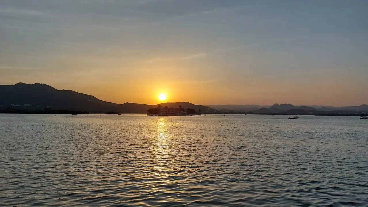 Tramonto sereno sul lago indiano con riflessi dorati sull'acqua.