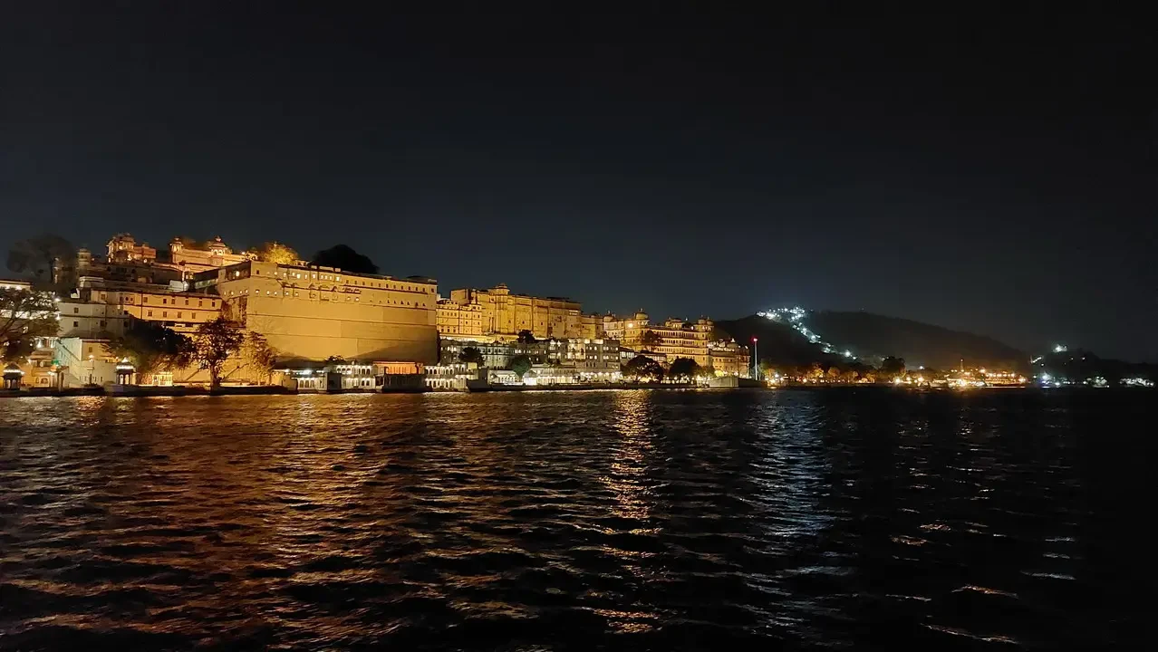 Un grande palazzo storico è splendidamente illuminato lungo il fiume di notte.