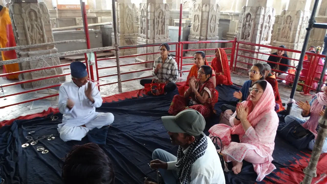 Un gruppo di persone è seduto in una sala con decorazioni architettoniche in India.