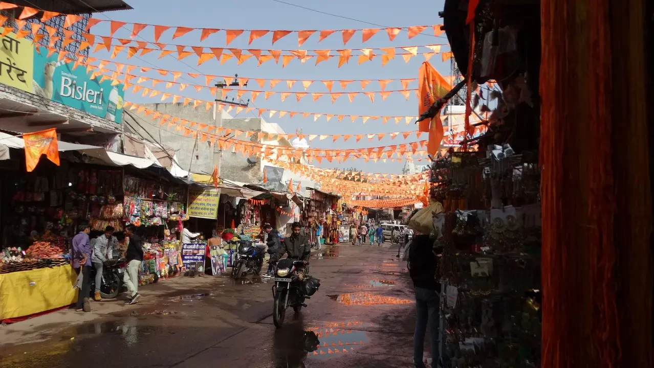 Una strada di mercato indiana decorata con striscioni arancioni e bancarelle.
