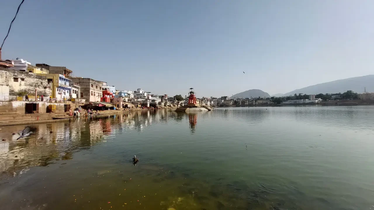 Paesaggio fluviale con abitazioni lungo la riva e colline sullo sfondo.