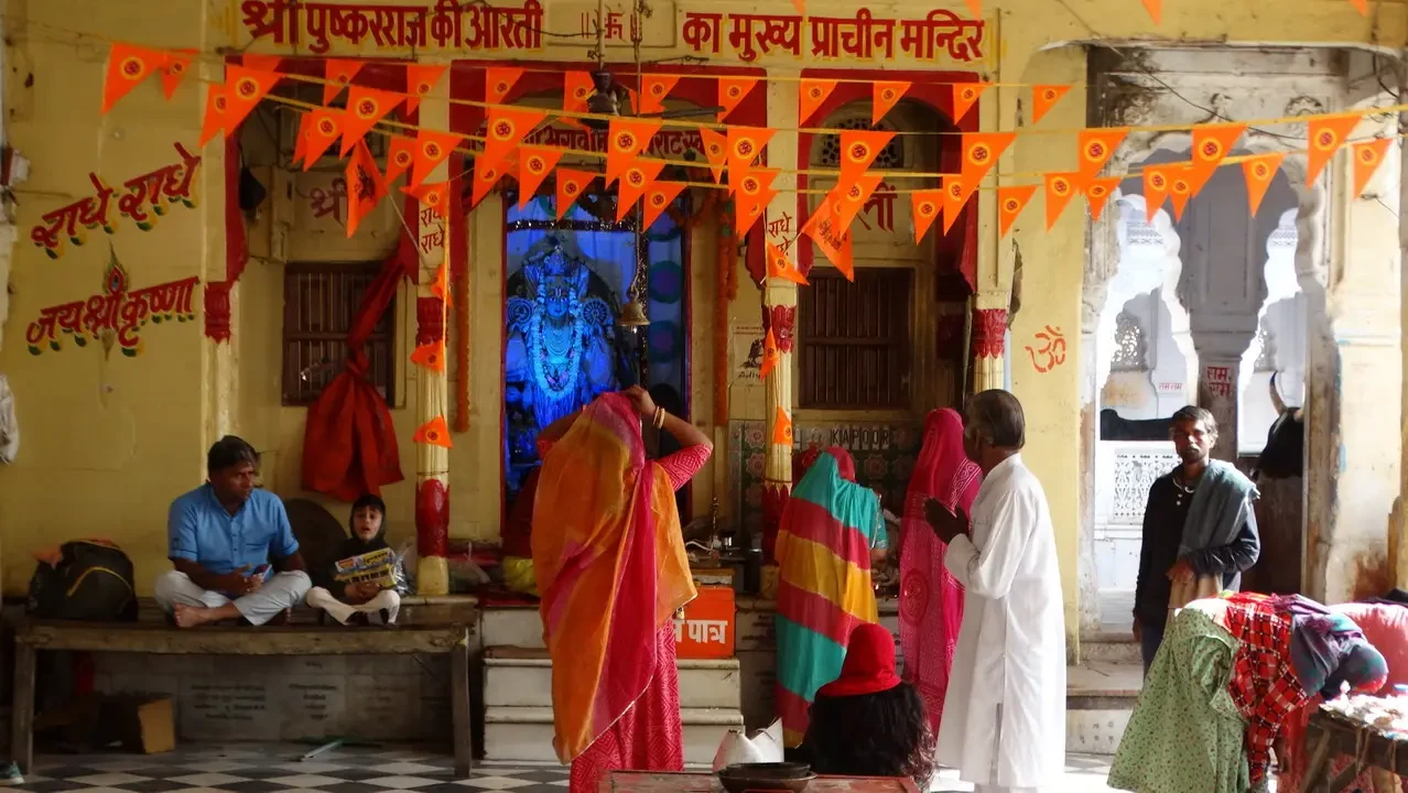 Persone in abiti tradizionali si radunano davanti all'ingresso di un tempio decorato in India.