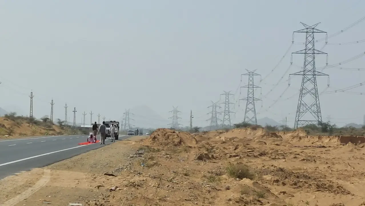 Una passeggiata lungo una strada di campagna in India con linee elettriche in lontananza.