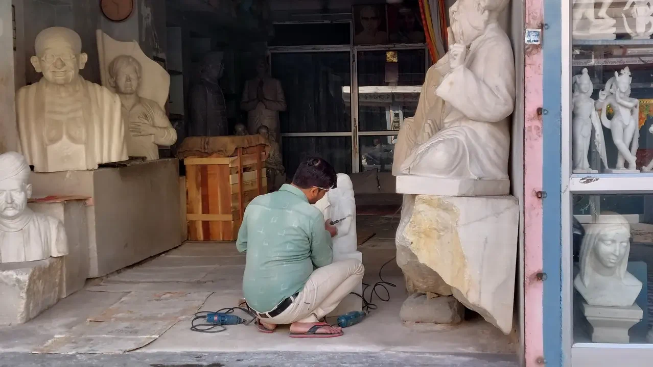 Scultori lavorano statue di pietra all'aperto in un laboratorio indiano.