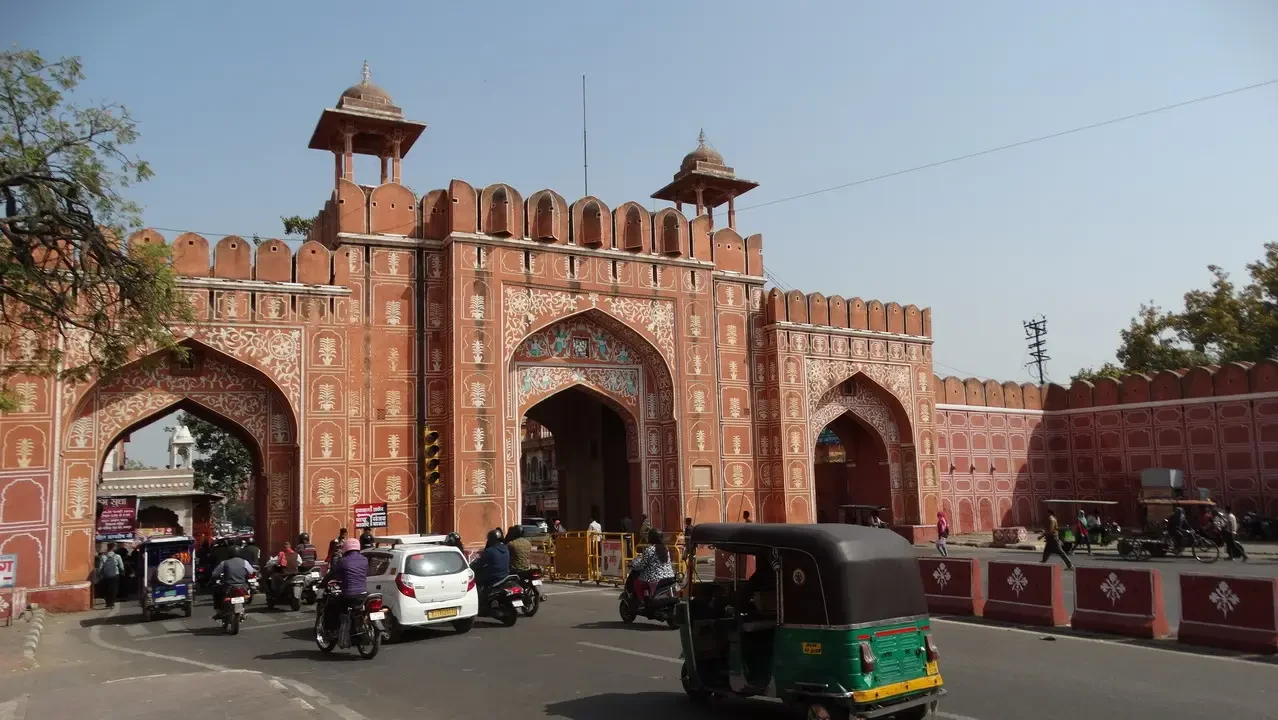 Portone monumentale rosso di Jaipur con traffico veicolare.