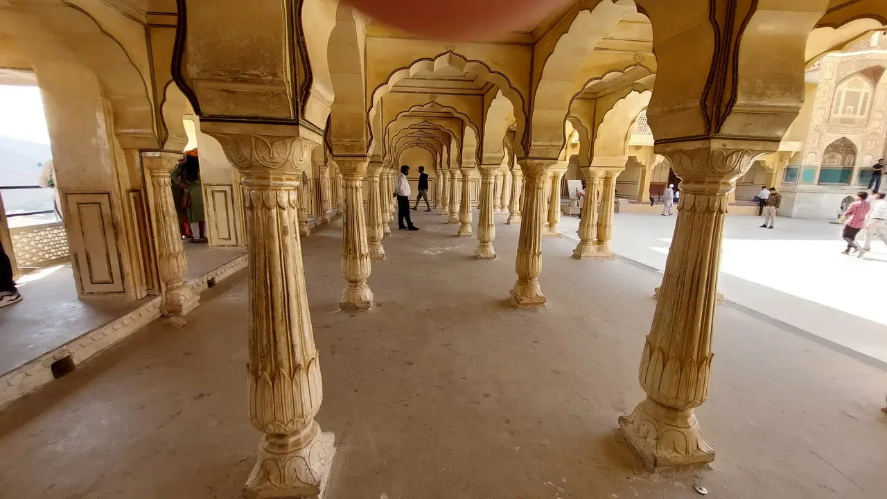 Una galleria colonnata in pietra gialla mostra un corridoio interno di un forte indiano.