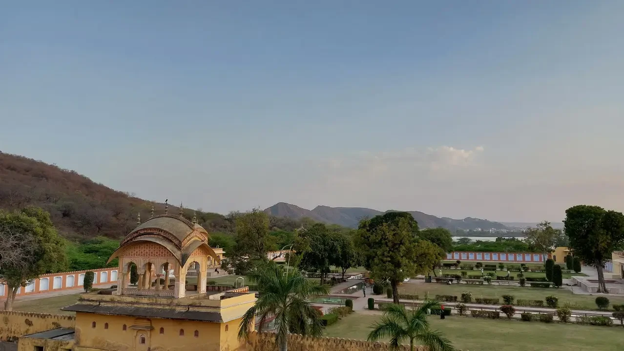 Un tempio indiano con un cortile e giardini si staglia su un paesaggio collinare.