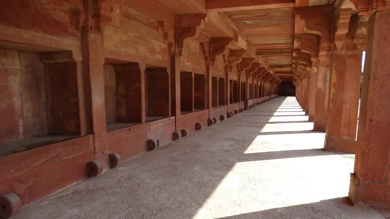 Un corridoio interno in pietra con archi e pilastri lungo una galleria.