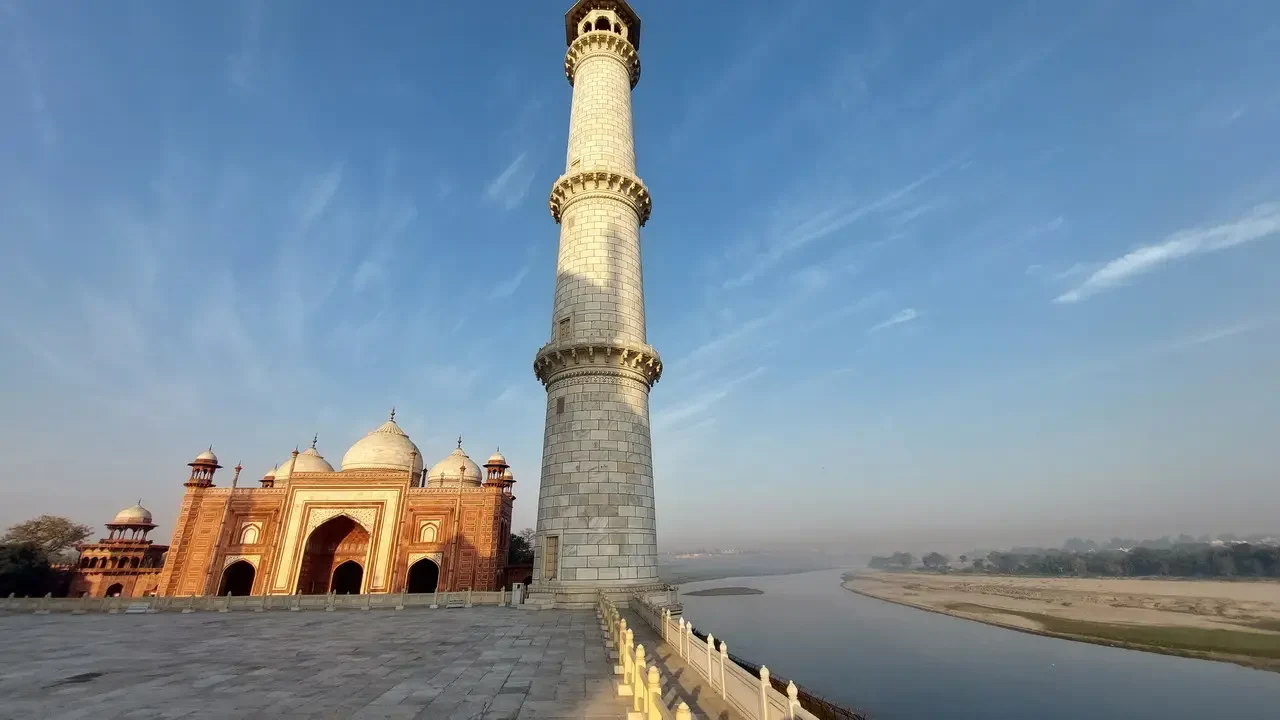 Il Taj Mahal domina il panorama con la sua maestosa guglia e la moschea in primo piano.