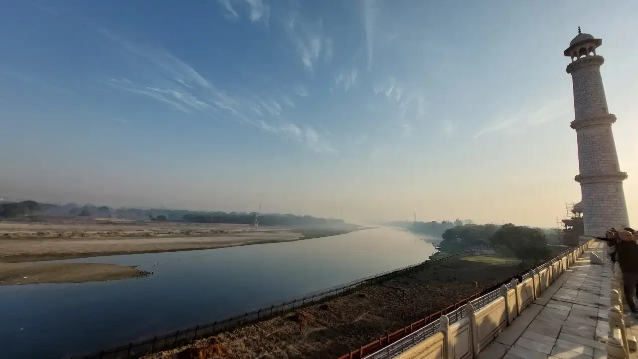 Il Taj Mahal è visibile lungo un fiume in India all'alba.