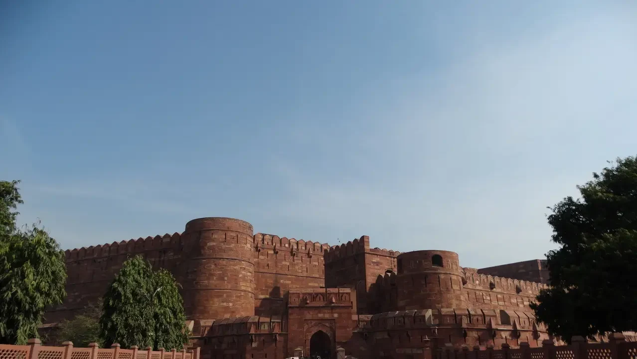 Vista panoramica delle imponenti mura del forte di Agra in India sotto un cielo azzurro.