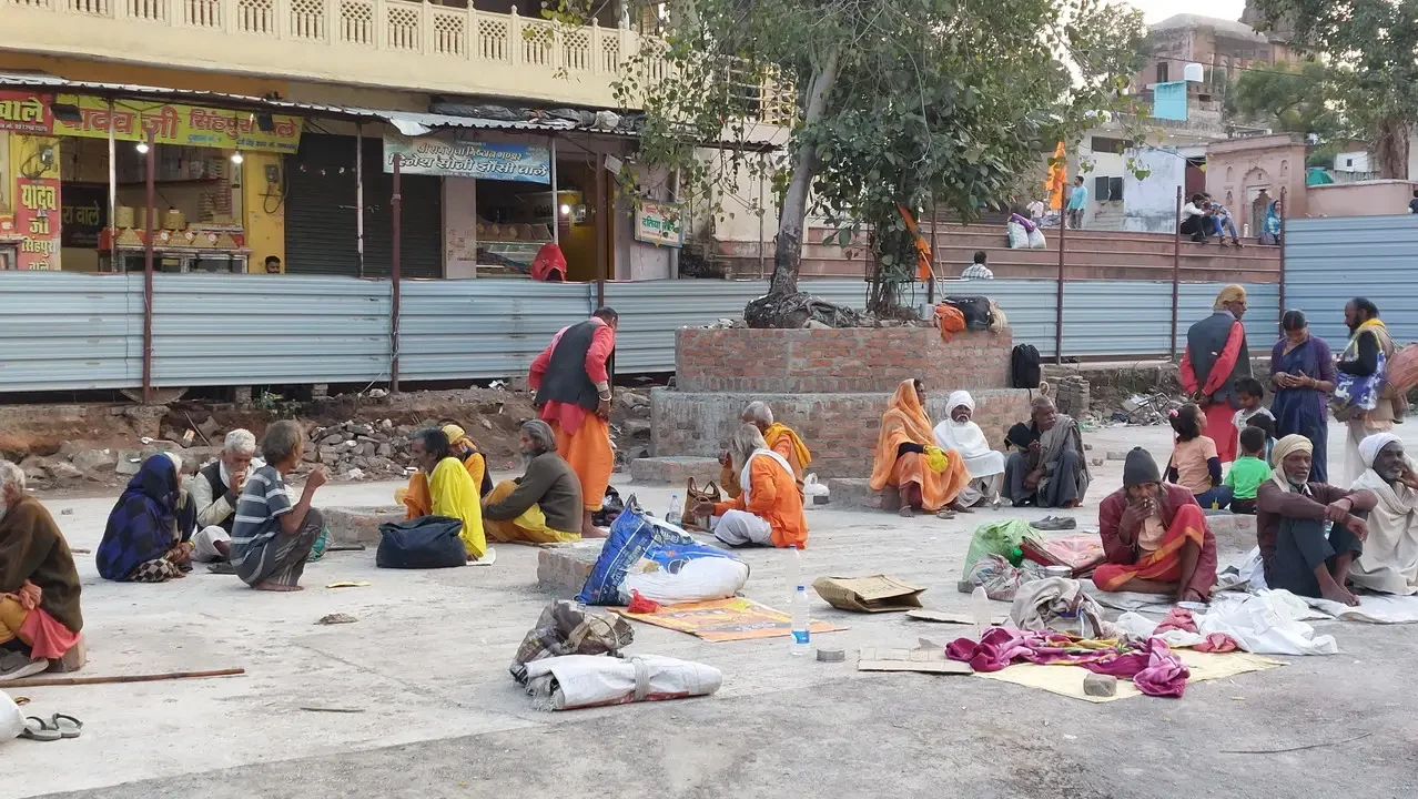 Un gruppo di persone è seduto all'aperto davanti a un edificio in India.
