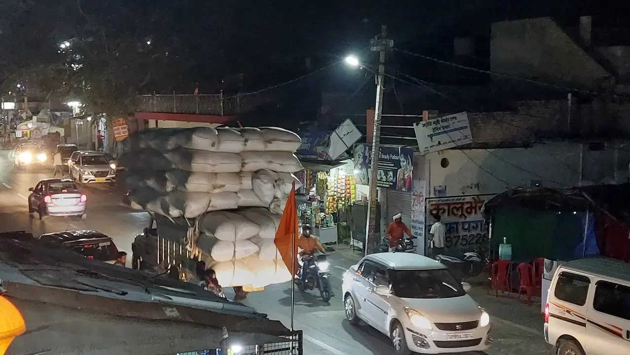 Un carico di balle di paglia trasportato su una strada trafficata in India di notte.