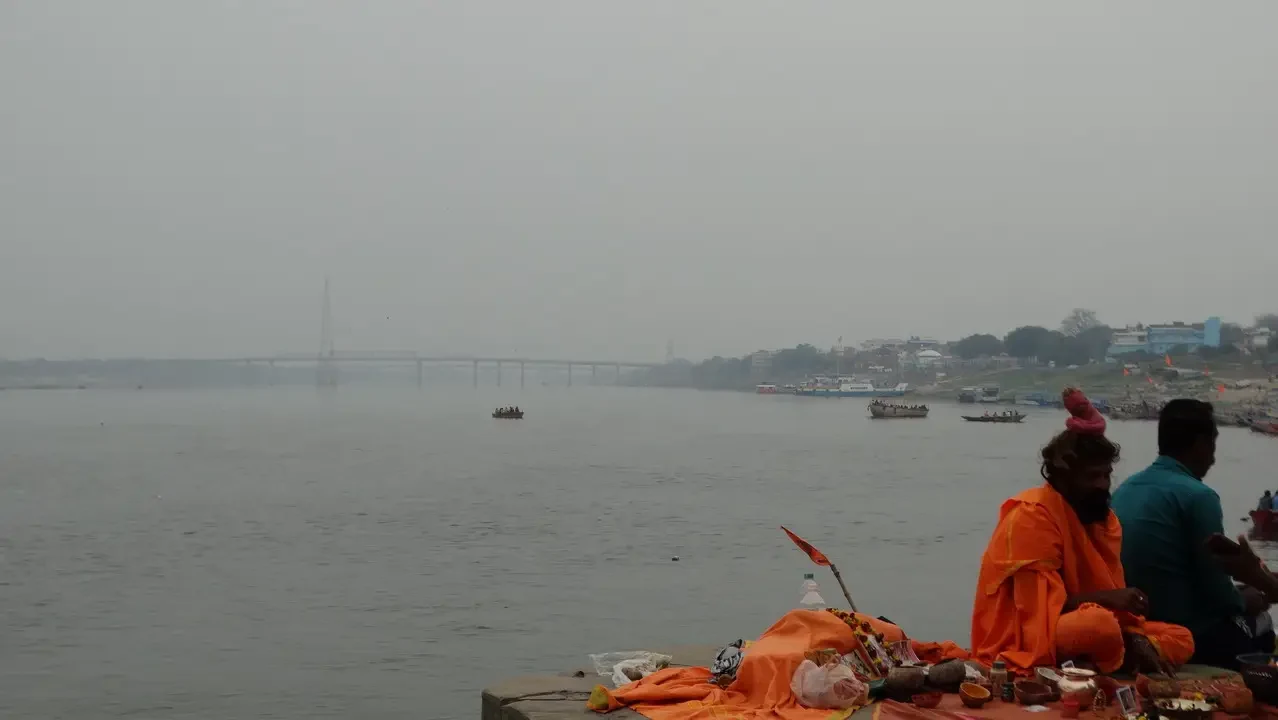 Sadhus vestiti di arancione siedono lungo la riva del fiume vicino a un ghat.