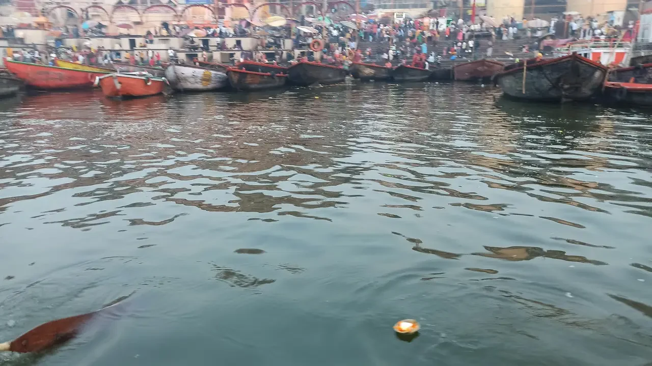 Una gondola o una barca tradizionale naviga su un fiume affollato in India.