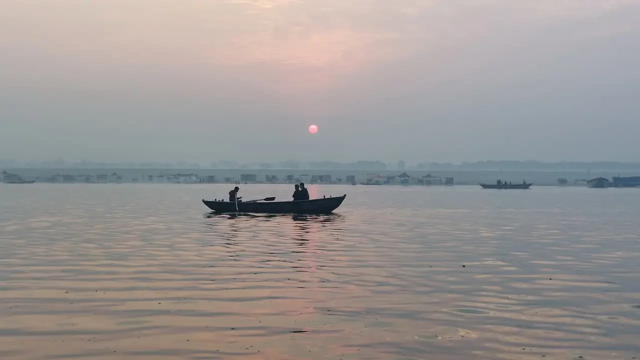 Una barca naviga su un fiume all'alba o al tramonto.
