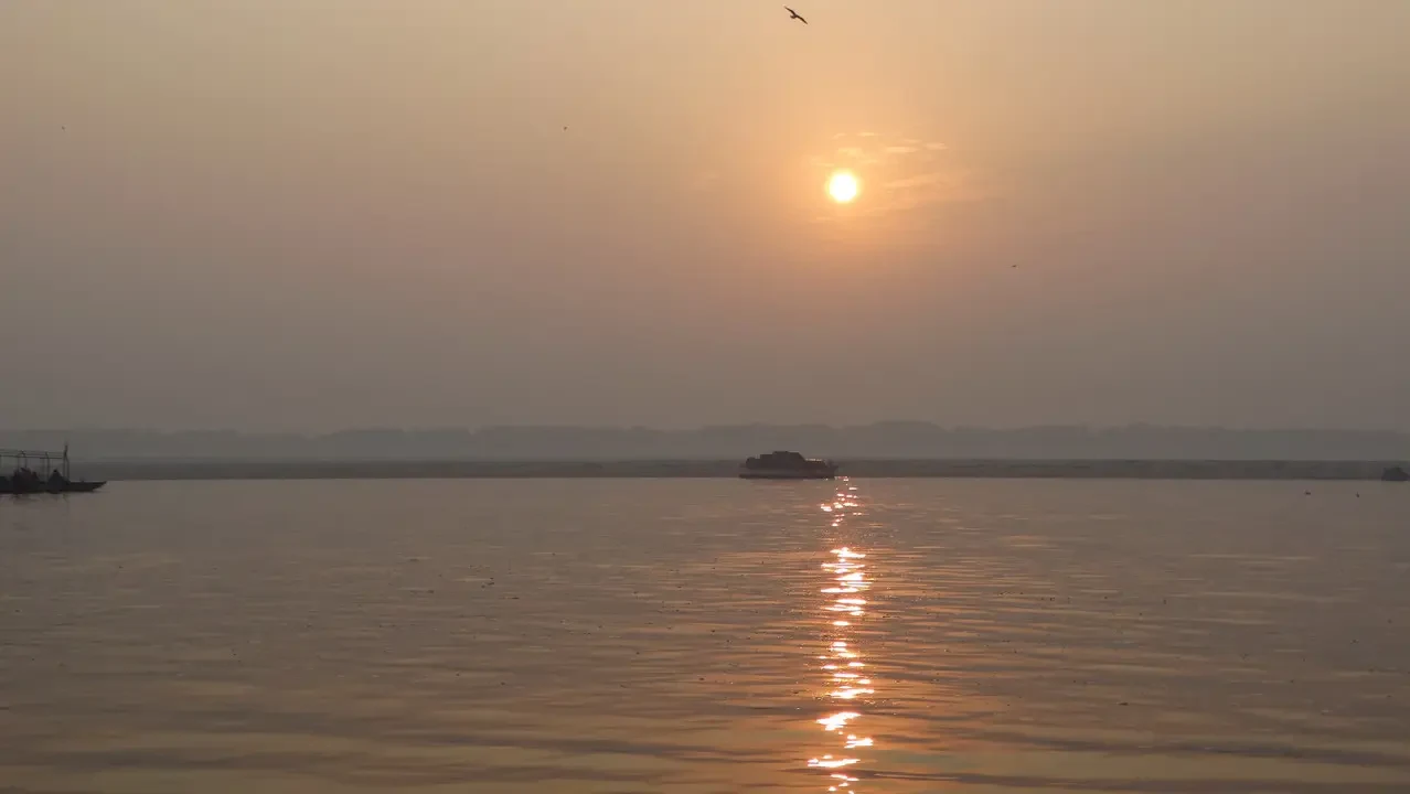 Un battello naviga su un fiume al tramonto in India.