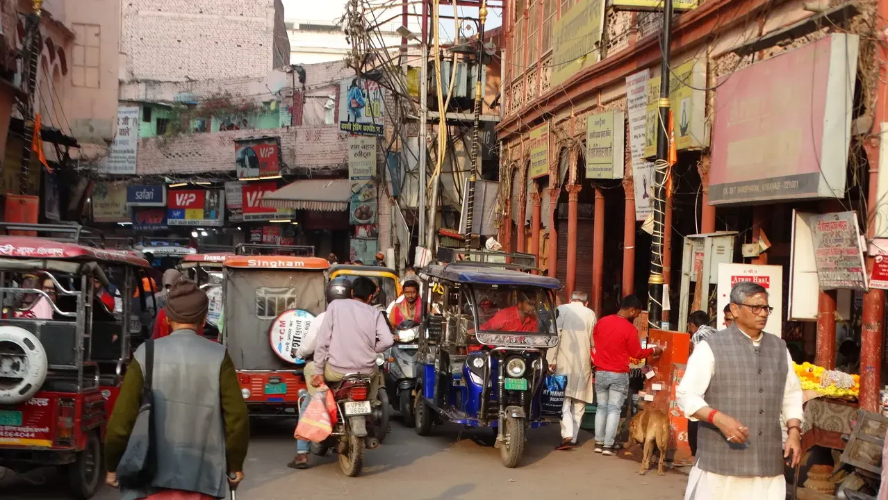 Una scena di strada trafficata a Varanasi con veicoli e persone in primo piano.