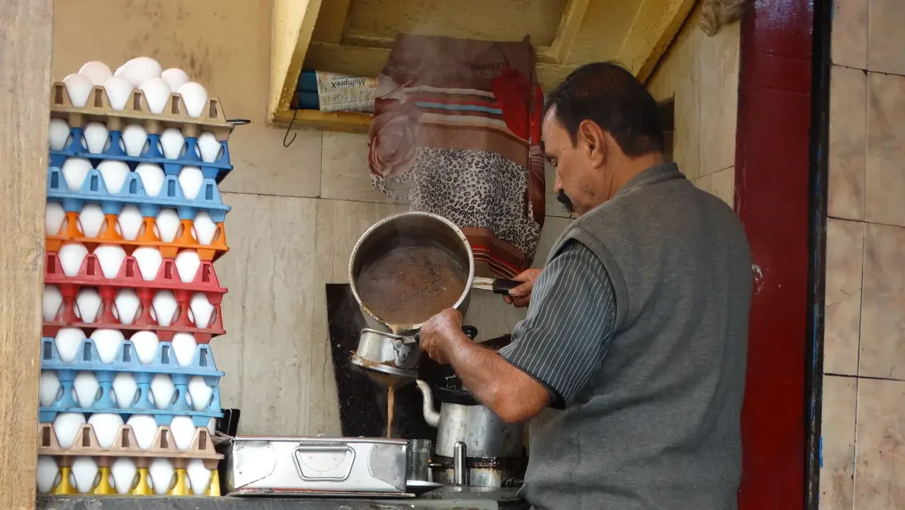 Un uomo prepara una bevanda tradizionale indiana in un ambiente domestico.
