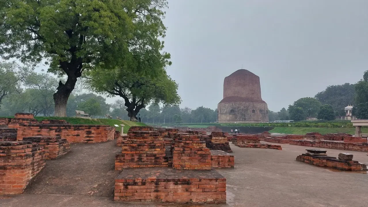 Una vista panoramica di una stupa in rovina con alberi sullo sfondo.