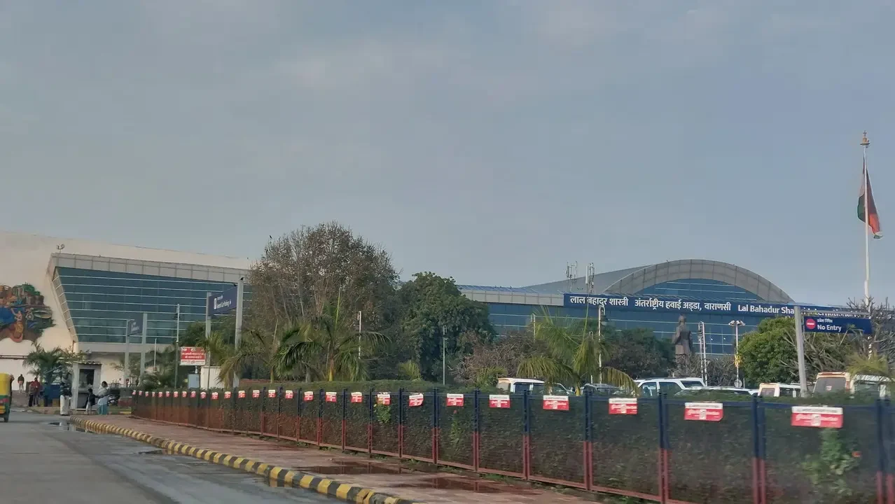 Vista dell'ingresso di un aeroporto indiano con recinzioni e strutture moderne.