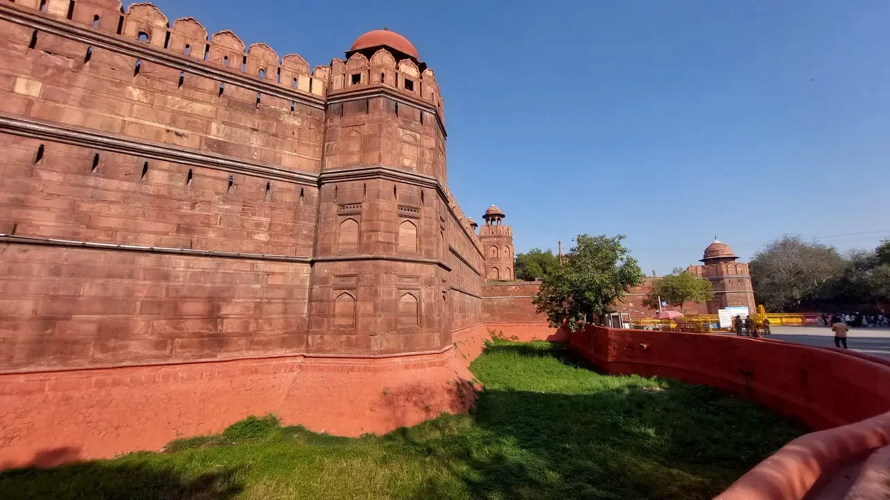 La cinta muraria rossa del Forte Rosso a Delhi in India sotto il sole.
