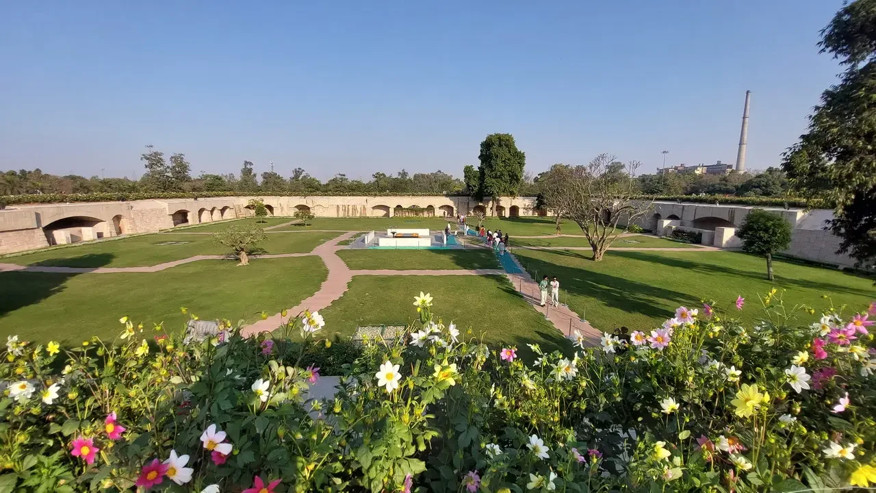 Giardino con archi e fiori in primo piano mostra un paesaggio sereno in India.