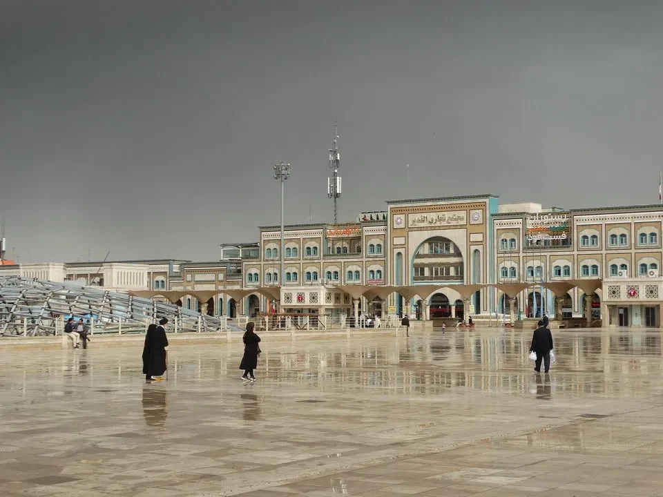 A square with historic buildings in Iran under a gray sky.