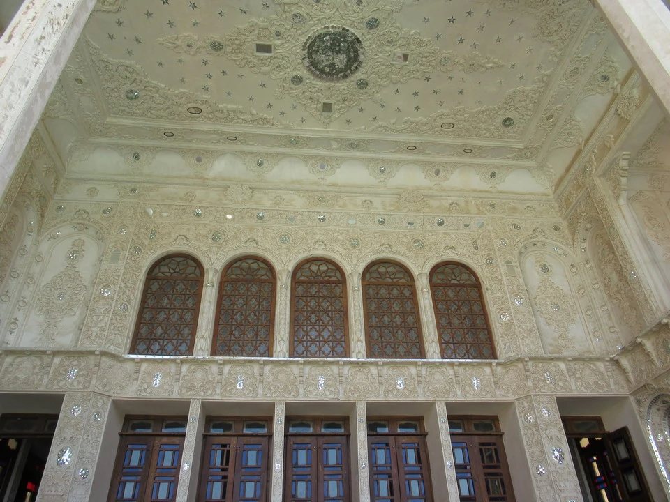 Interno sontuoso di un edificio storico in Iran con soffitto decorato e finestre a riquadri.