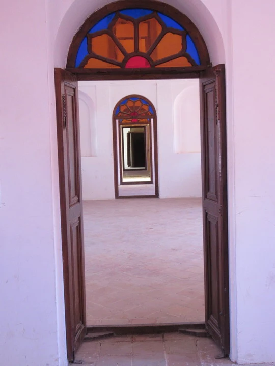 Interno di un edificio con archi decorati in mattoni rossi.