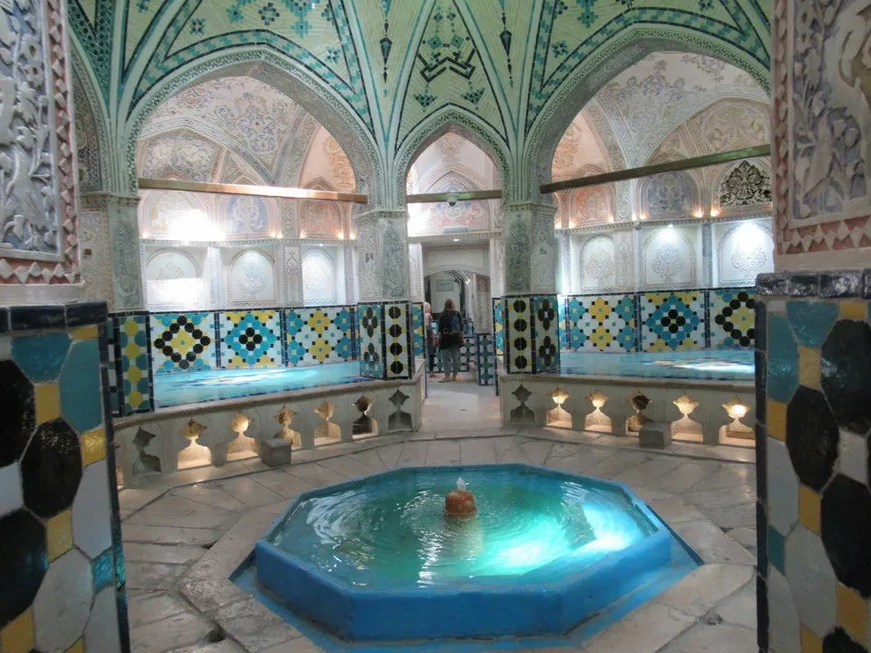 Interno di una vasca termale decorata in stile islamico con mosaici blu e verdi.