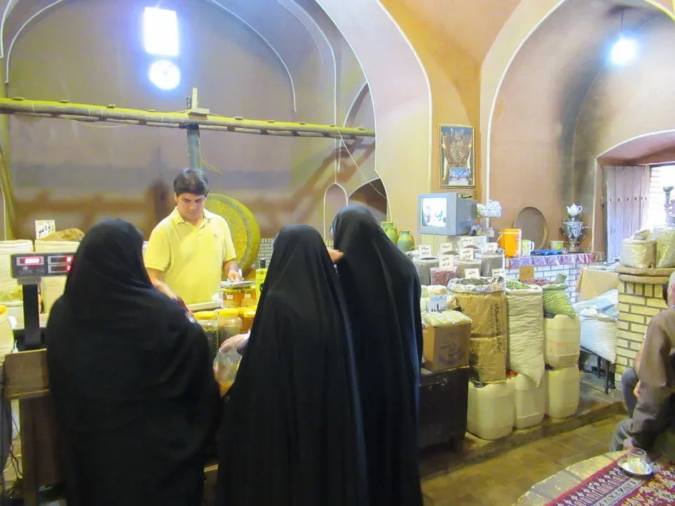 Mercato di Kashan con venditori e merci esposte all'interno di un cortile arcato.
