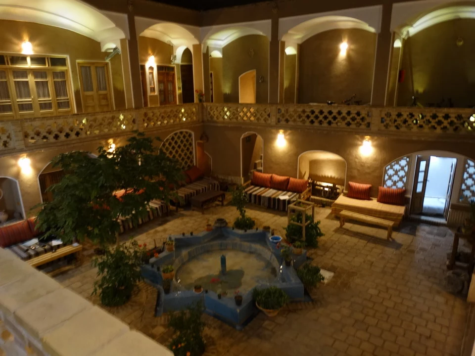 Interno di un hotel tradizionale iraniano con cortile interno e archi decorati.