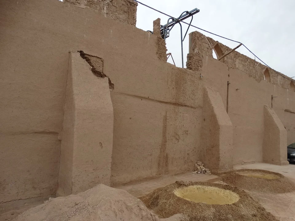 Mura di argilla della città di Yazd in Iran con materiali da costruzione in primo piano.